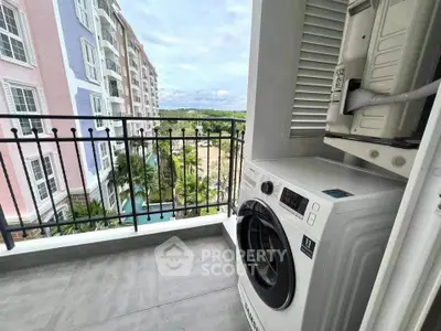 Charming balcony with washing machine and scenic view of colorful buildings and lush greenery.
