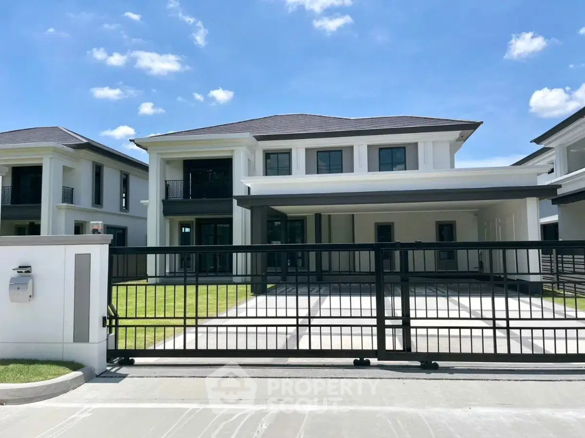 Luxurious modern house with spacious driveway and elegant facade under clear blue sky.