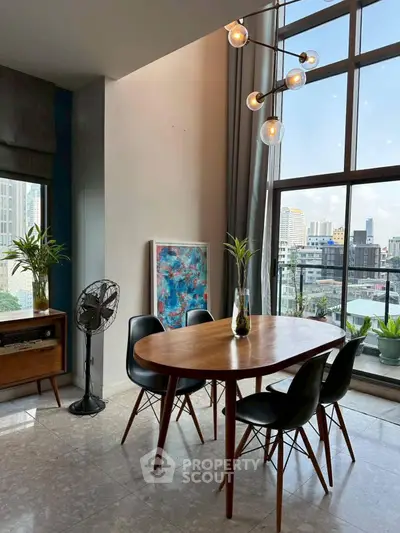 Stylish dining area with modern furniture and city view, featuring large windows and chic lighting.