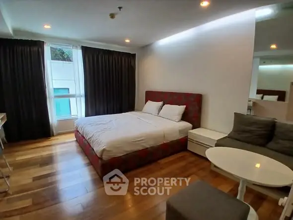 Spacious bedroom with modern decor and large windows in a stylish apartment.