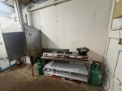 Industrial kitchen space with gas stoves and ventilation system, ideal for commercial use.