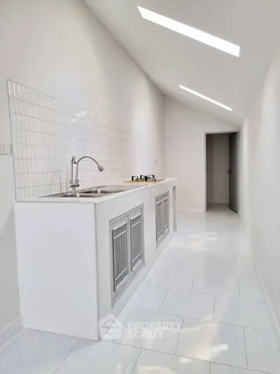 Sleek modern kitchen with minimalist design and gas stove in bright white interior.