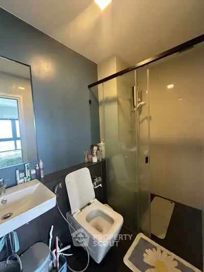 Modern bathroom with sleek design, featuring a glass shower enclosure and contemporary fixtures.