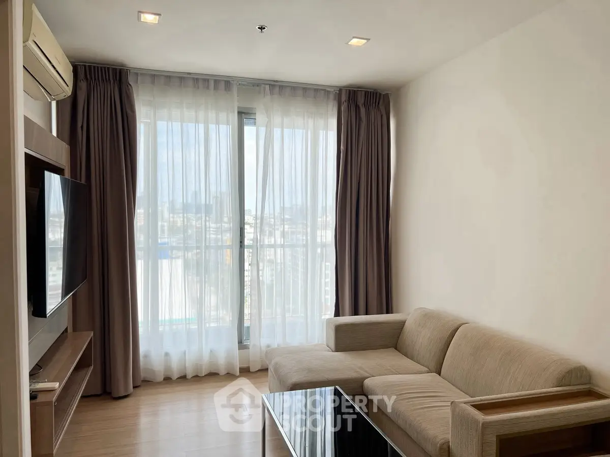 Modern living room with large windows and cozy beige sofa in a high-rise apartment.