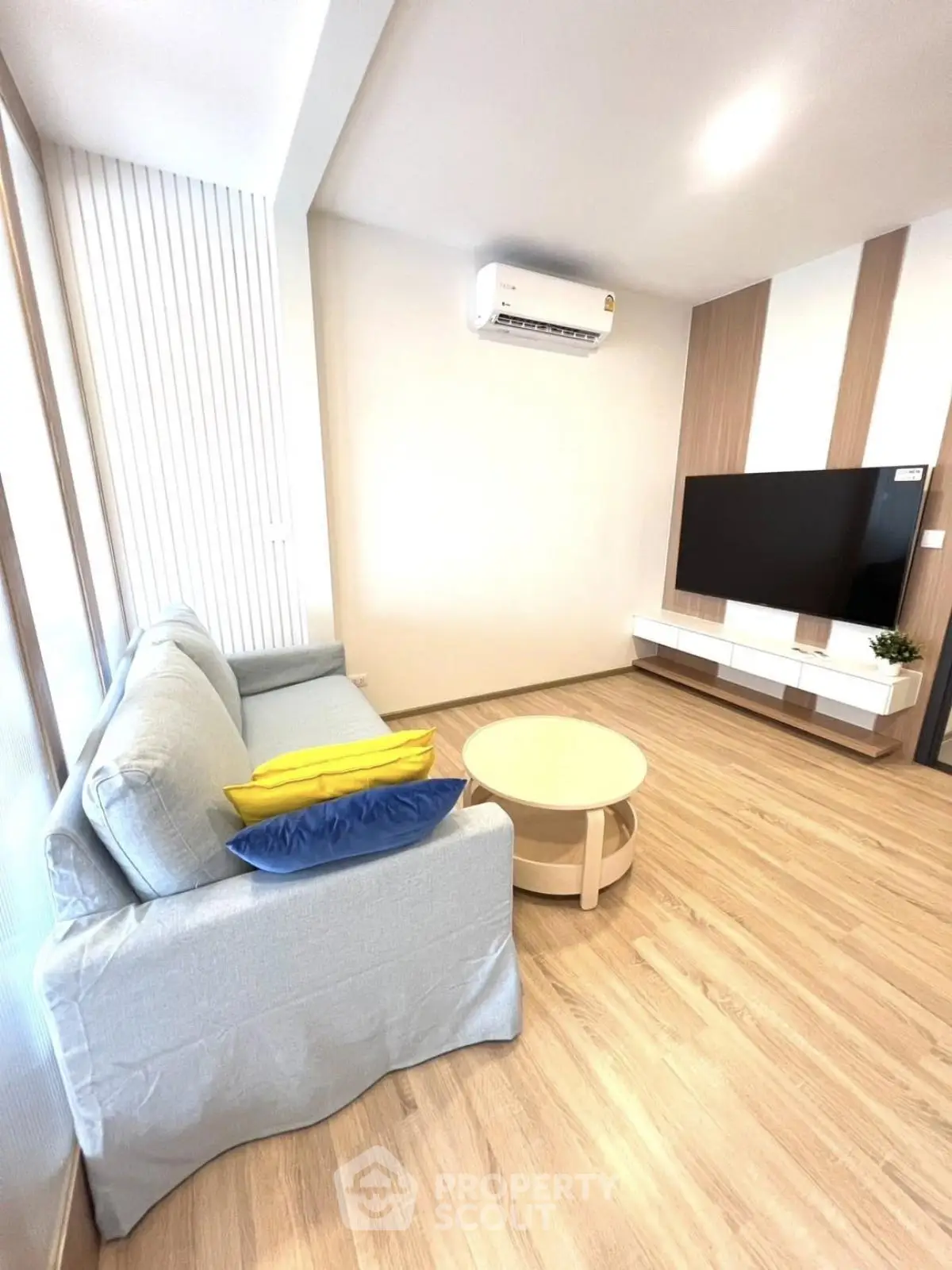 Modern living room with sleek design, featuring a cozy sofa, flat-screen TV, and stylish wooden flooring.