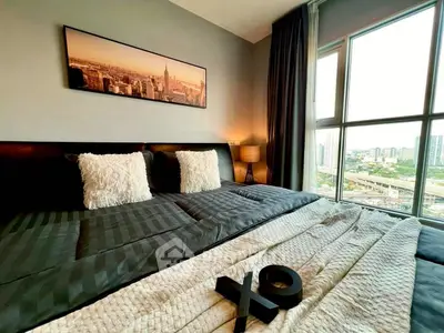 Luxurious bedroom with city view, plush bedding, and elegant decor in modern apartment.