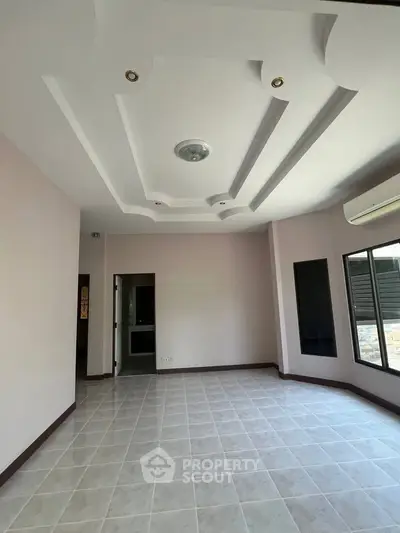 Spacious empty room with modern ceiling design and large windows