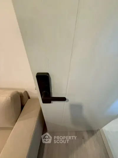 Modern interior door with sleek handle next to a beige sofa in a stylish living space.