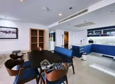 Modern open-layout kitchen and dining area with sleek blue cabinetry and contemporary furniture.