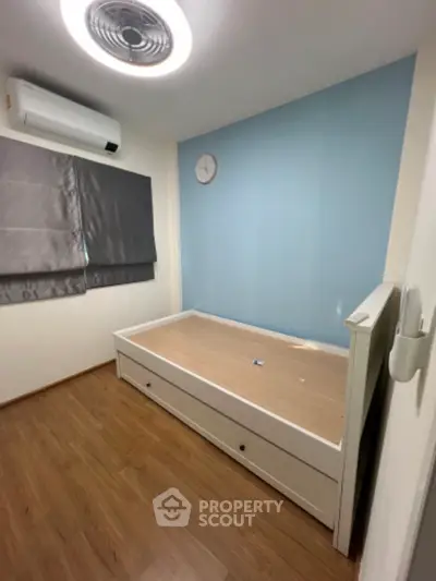 Cozy minimalist bedroom with wooden flooring and modern air conditioning unit.
