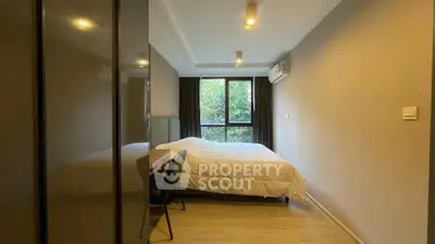 Modern bedroom with large window and stylish decor in a cozy apartment.