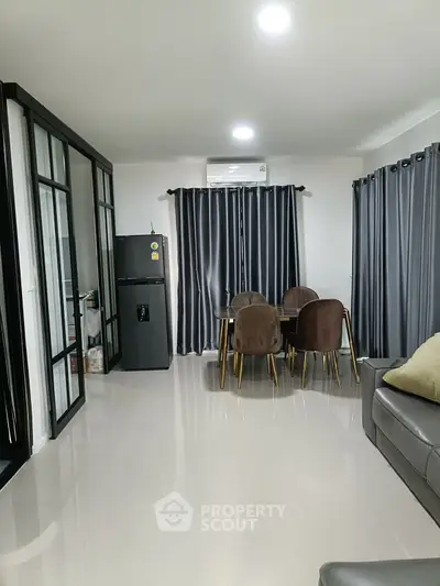 Modern living room with sleek furniture and dining area, featuring large windows and elegant curtains.