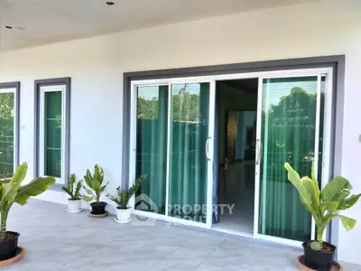 Spacious balcony with sliding glass doors and potted plants, perfect for relaxation.