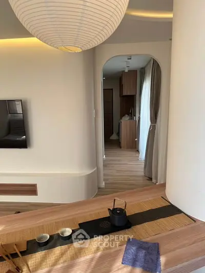 Elegant modern living room with minimalist decor and wooden flooring, featuring a cozy tea setup.