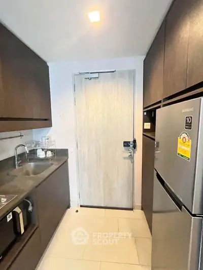 Modern kitchen with sleek cabinetry and stainless steel fridge in compact layout.