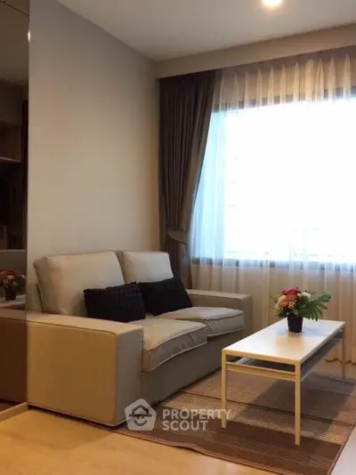 Cozy living room with elegant sofa and natural light through large window.