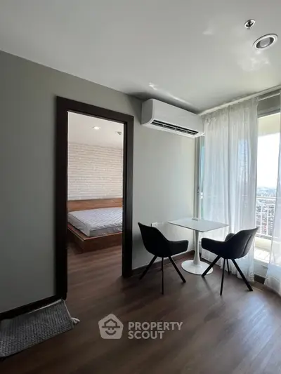 Modern apartment interior with cozy dining area and bedroom view, featuring sleek furniture and natural light.