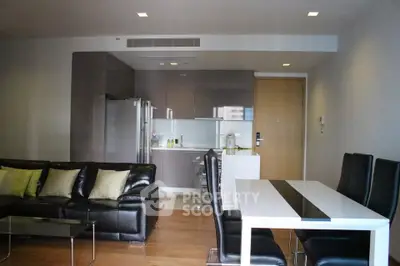 Modern open-plan living room with sleek kitchen and dining area, featuring stylish furniture and contemporary design.