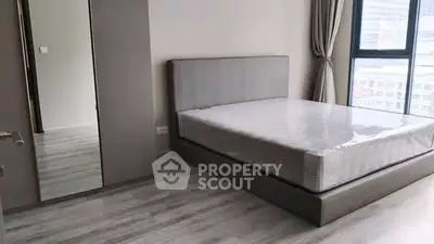 Modern bedroom with large window and sleek furnishings in urban apartment.