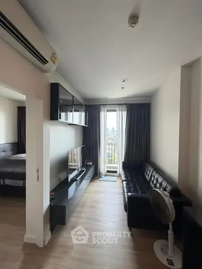 Modern living room with sleek black sofa and city view from balcony, perfect for urban living.