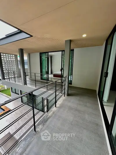 Modern balcony with sleek railing overlooking stylish interior and garden view.