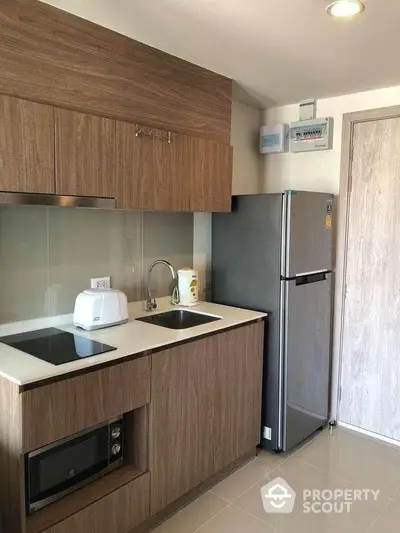 Modern compact kitchen with sleek wooden cabinets and stainless steel appliances