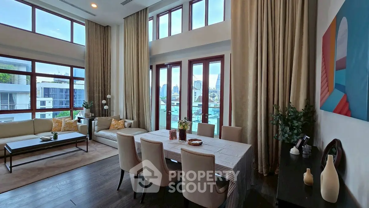 Luxurious living room with high ceilings and elegant dining area, featuring large windows and modern decor.