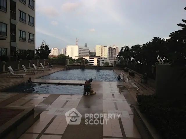 Luxurious rooftop pool with city skyline view in modern residential building.