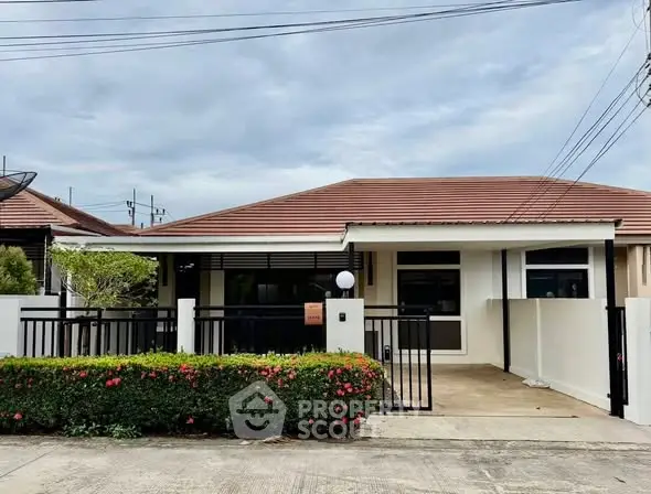 Charming single-story house with a tiled roof and gated driveway, perfect for cozy living.