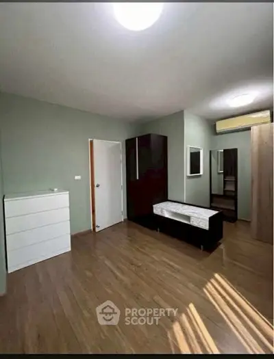 Spacious bedroom with wooden flooring and modern furniture, ideal for comfortable living.
