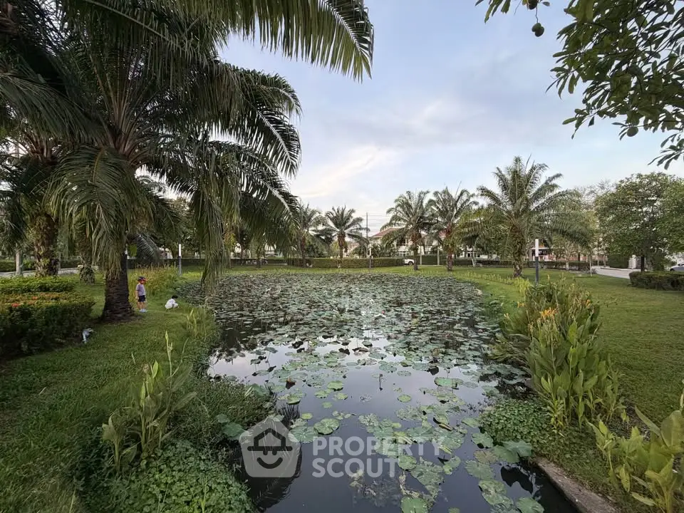 Serene garden view with lush greenery and tranquil pond in a residential area.
