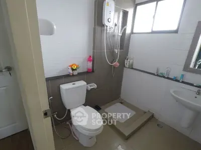 Modern bathroom with shower, toilet, and sink in a well-lit space.
