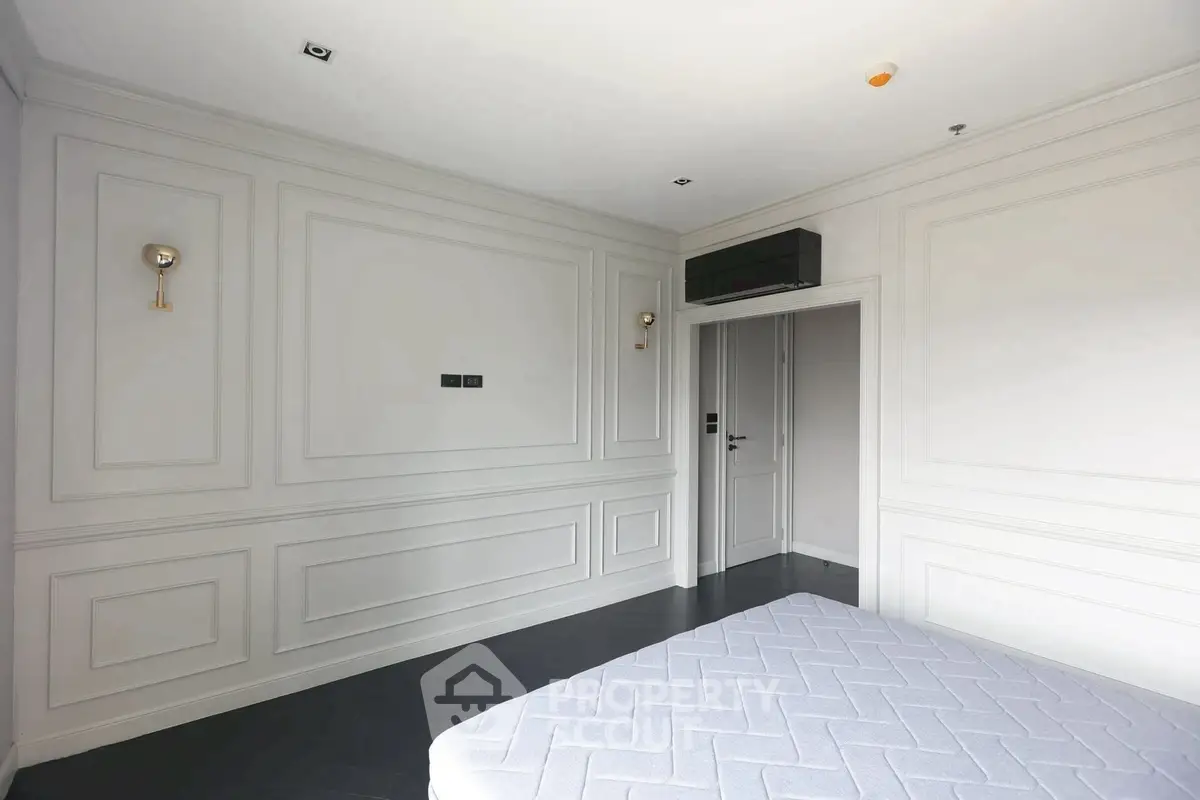 Spacious bedroom with elegant wall paneling and modern lighting