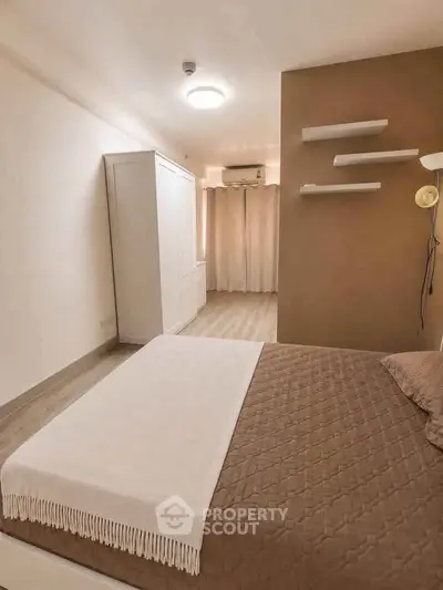 Spacious bedroom with modern decor and ample natural light, featuring a cozy bed and stylish shelving.