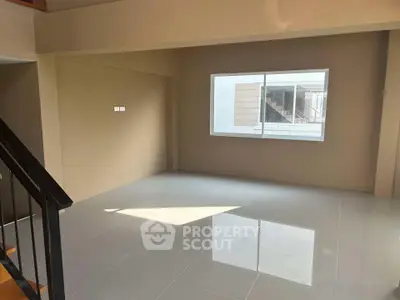 Spacious empty room with large window and glossy tiled floor, perfect for customization.