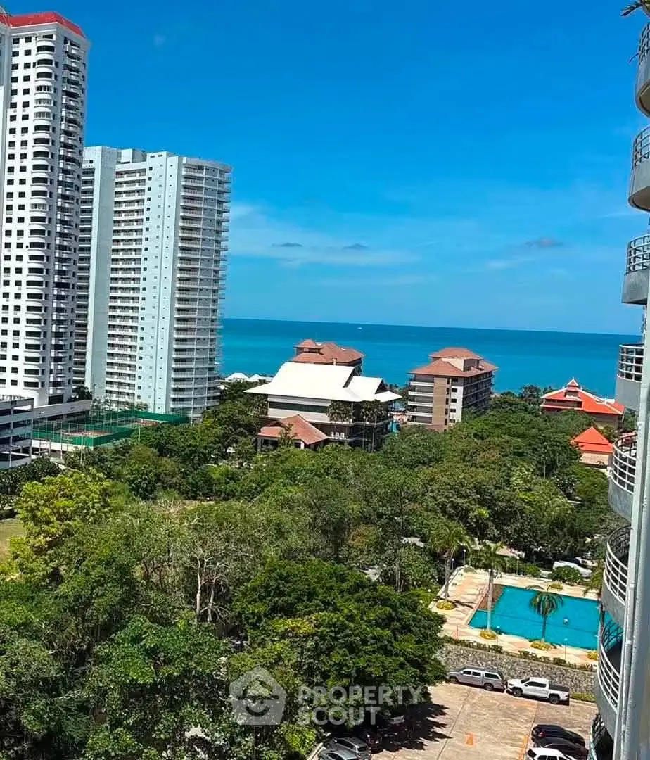 Stunning ocean view from high-rise building with lush greenery and pool area.