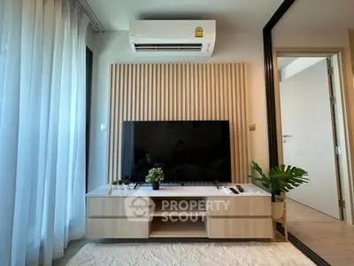 Modern living room with sleek TV setup and air conditioning, featuring stylish decor and natural light.