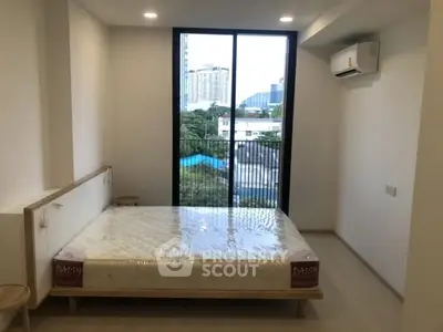 Modern bedroom with large window and city view, featuring air conditioning and minimalist design.