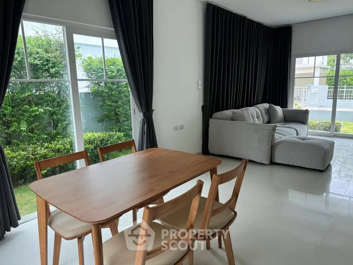Spacious living room with modern furniture and large windows overlooking a lush garden.