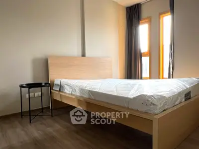 Modern bedroom with wooden flooring and natural light from large windows.