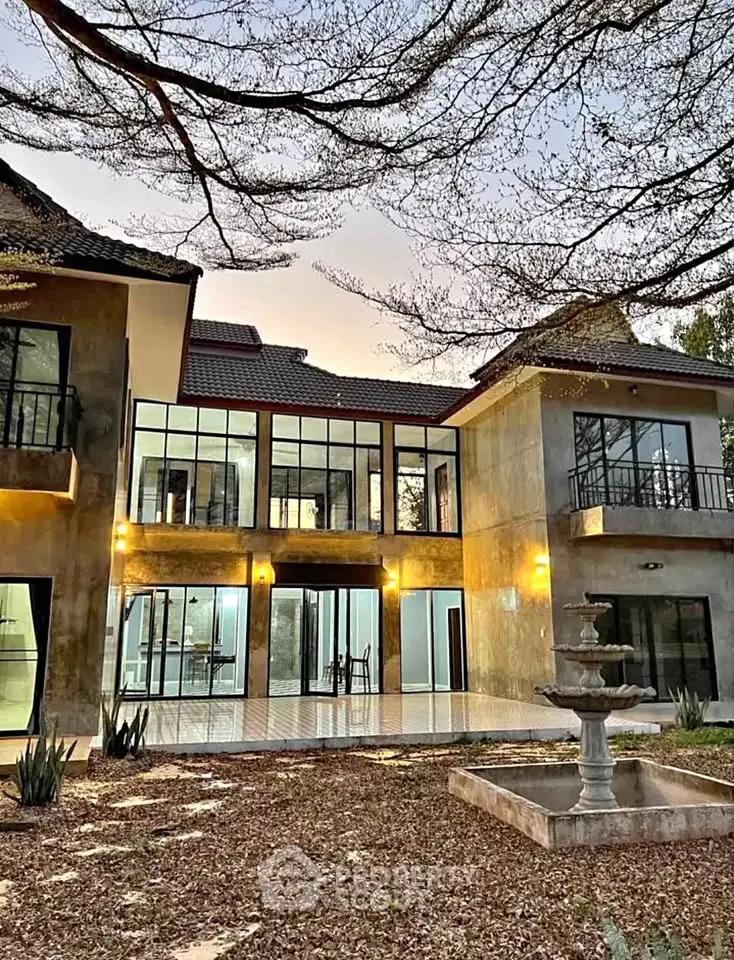 Stunning modern home with large windows and elegant courtyard fountain at sunset.