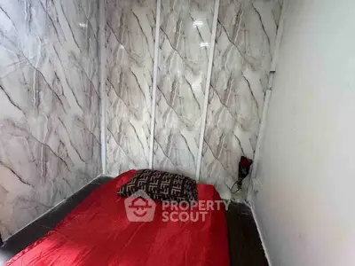 Cozy bedroom with marble-patterned walls and red bedding