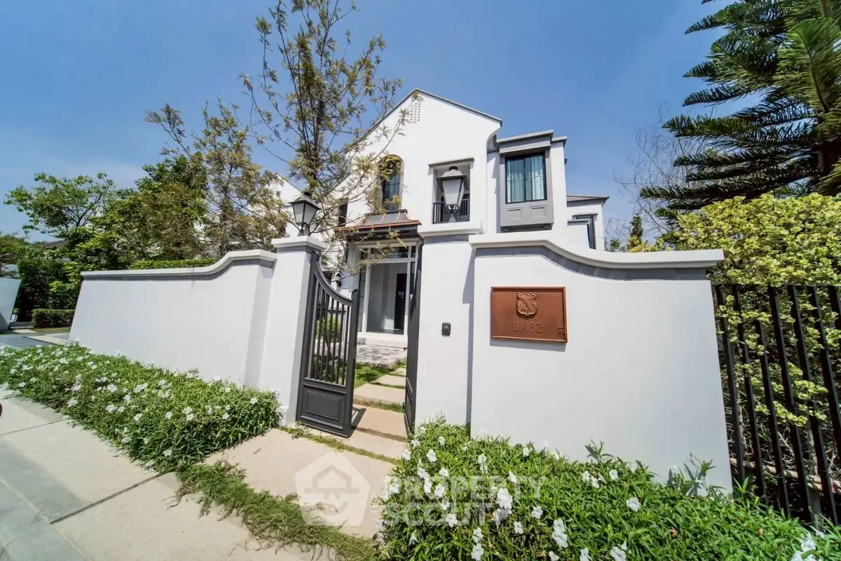 Stunning white villa with elegant entrance and lush greenery, perfect for luxury living.