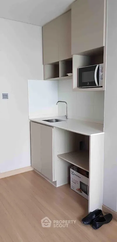 Modern compact kitchen with sleek cabinetry and built-in microwave, perfect for urban living.