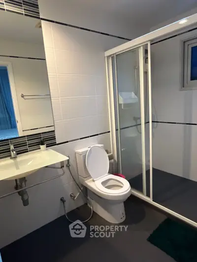 Modern bathroom with glass shower and sleek fixtures in contemporary home.