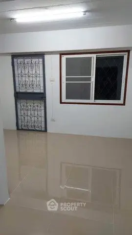 Spacious interior with tiled flooring and secure window grilles, ideal for modern living.