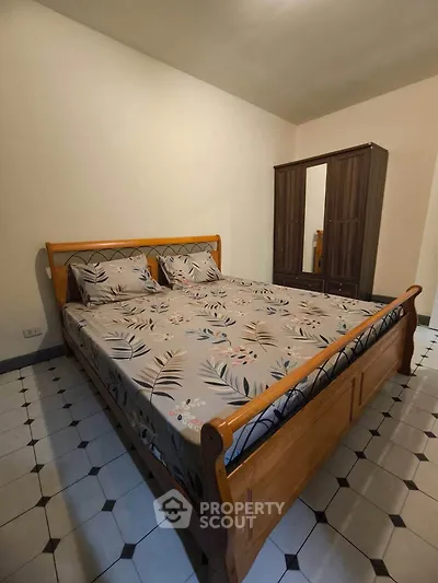 Cozy bedroom with wooden bed and wardrobe, featuring stylish tiled flooring.