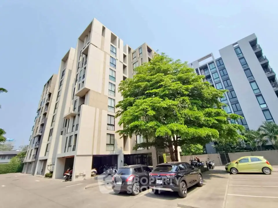 Modern apartment building with parking and lush greenery, ideal urban living.