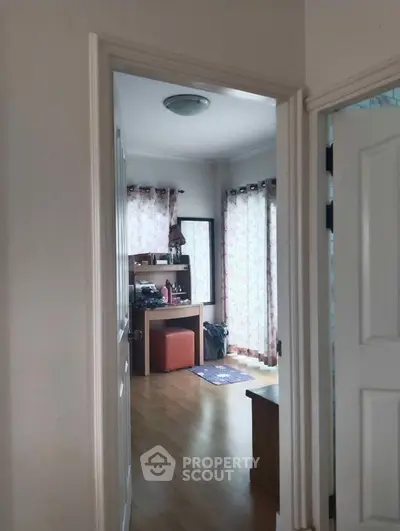 Inviting and cozy living space with natural light, elegant curtains, and hardwood floors, perfect for comfortable urban living.