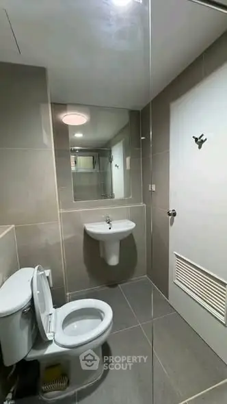 Modern bathroom with sleek fixtures and large mirror in contemporary apartment.
